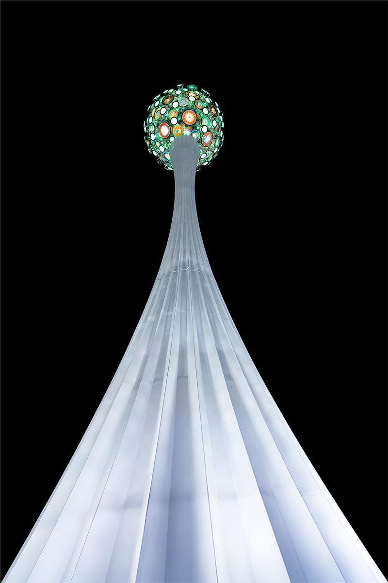 《仙泡兒》是由彩色玻璃球體及百褶裙擺柱身組合成蒲公英雌蕊意象，並使用金屬白色烤漆為百褶裙擺柱身鋪面，以及亮面不鏽鋼圓盤組成球體